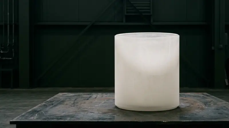 A white fused-quartz crucible on a dark workbench