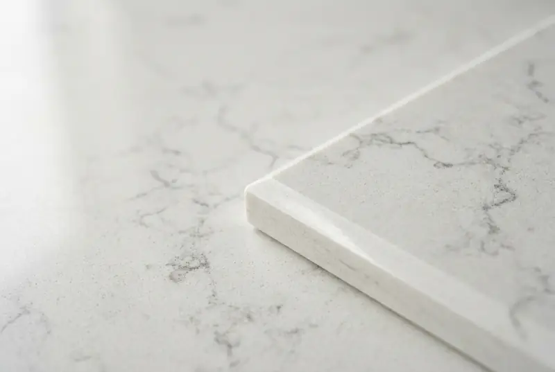 The polished edge of a white engineered quartz slab with grey veining
