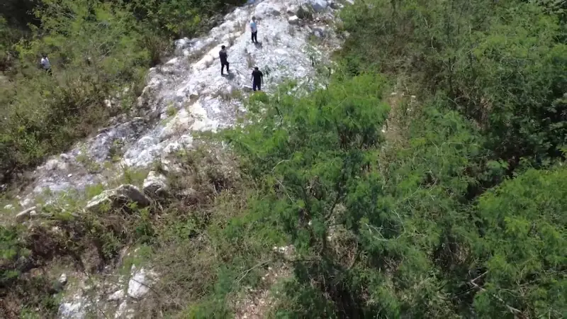 Aerial view of a white quartz vein on a hillside, with three people standing on it